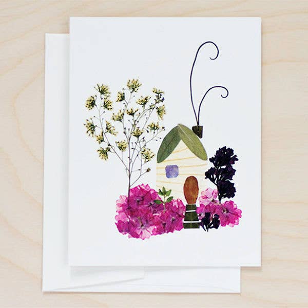 A cream coloured greetings card featuring a digital print of pressed flowers arranged in the shape of a house and a tree