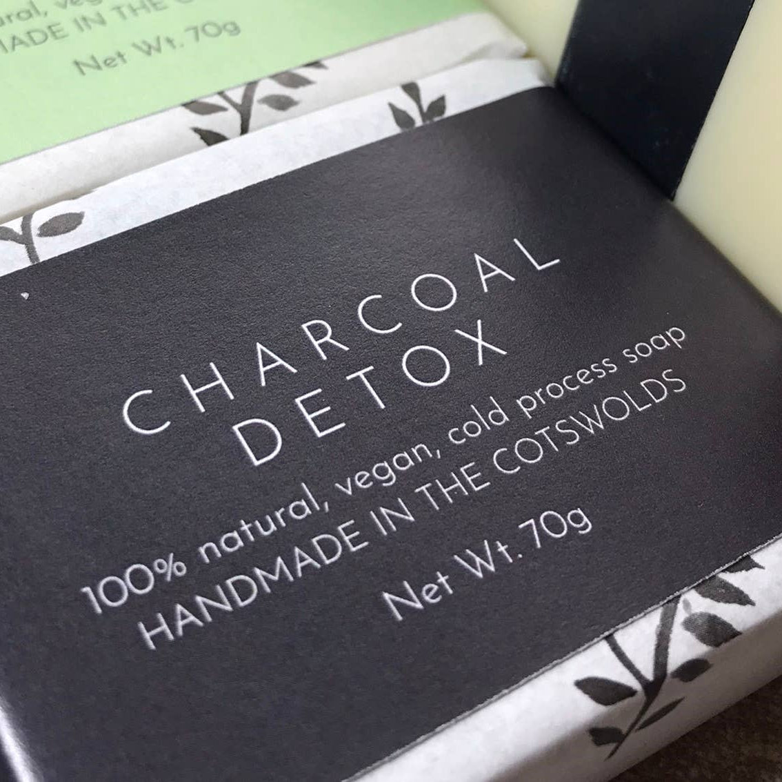 Packaged bar of The Lane Natural Skincare Company Charcoal Detox Soap with black label and white and green design elements.