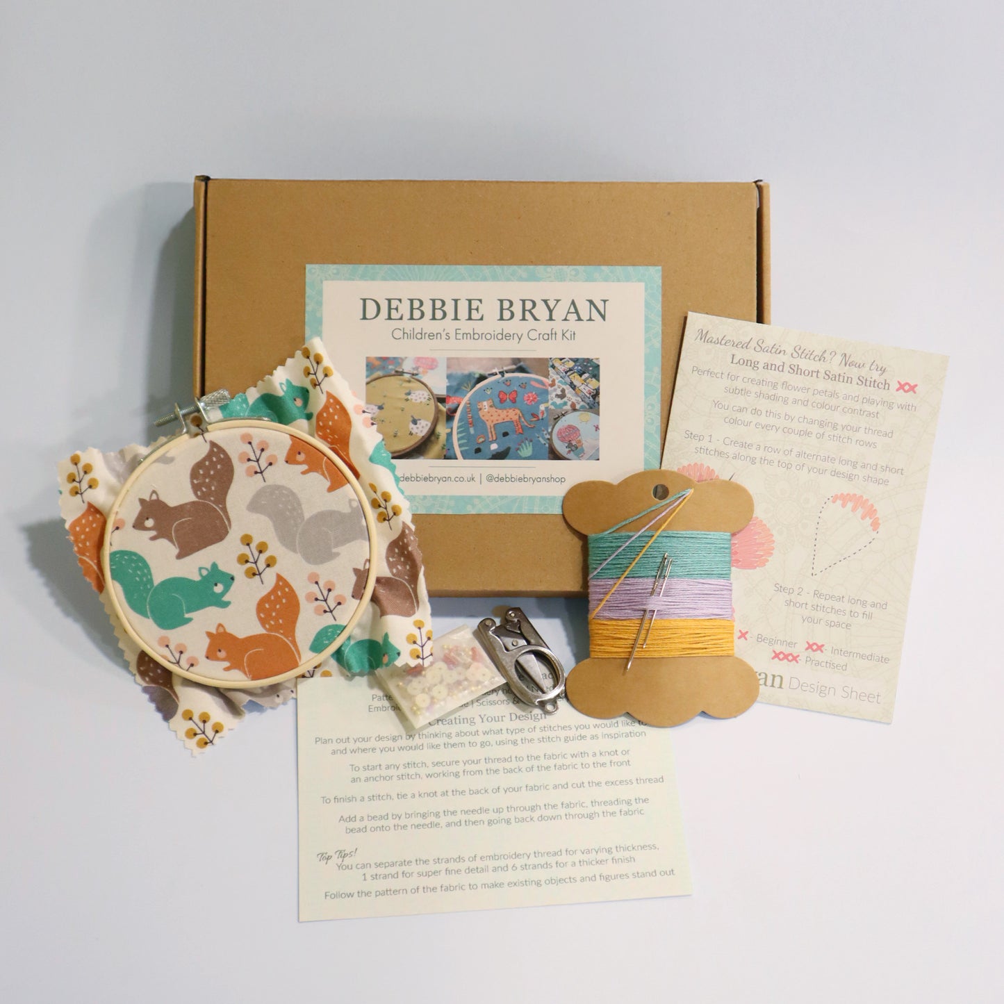 Children's embroidery craft kit with materials and instructions on a light gray background