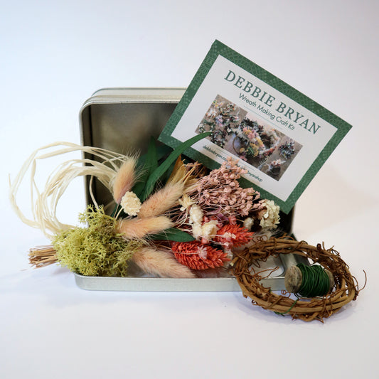 Wreath making craft kit with dried flower bunch, metal tin box and small vine wreath on a white background.