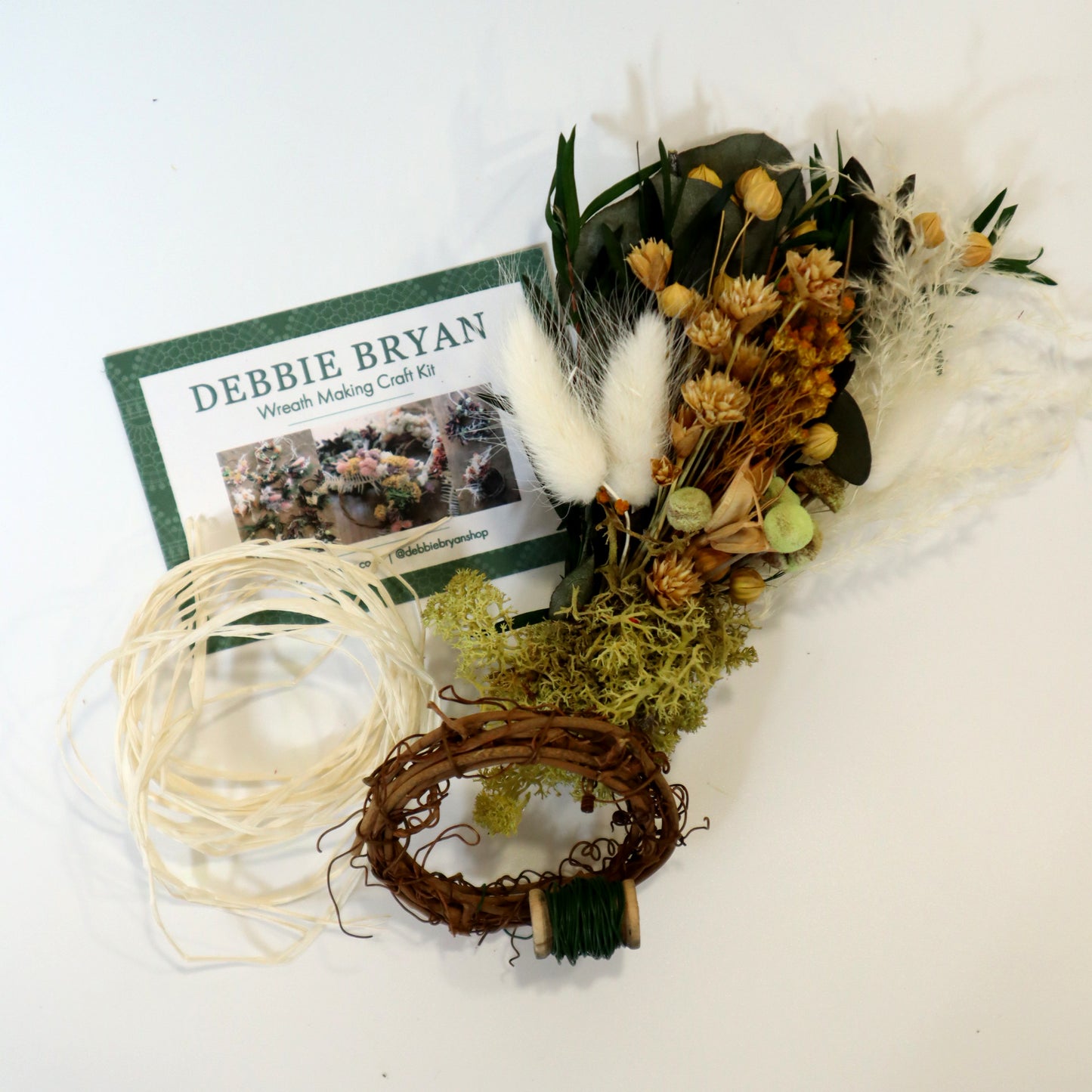 Small dried flower bunch with green preserved moss wrapped around the base and a small vine wreath with a green floristry wire attached