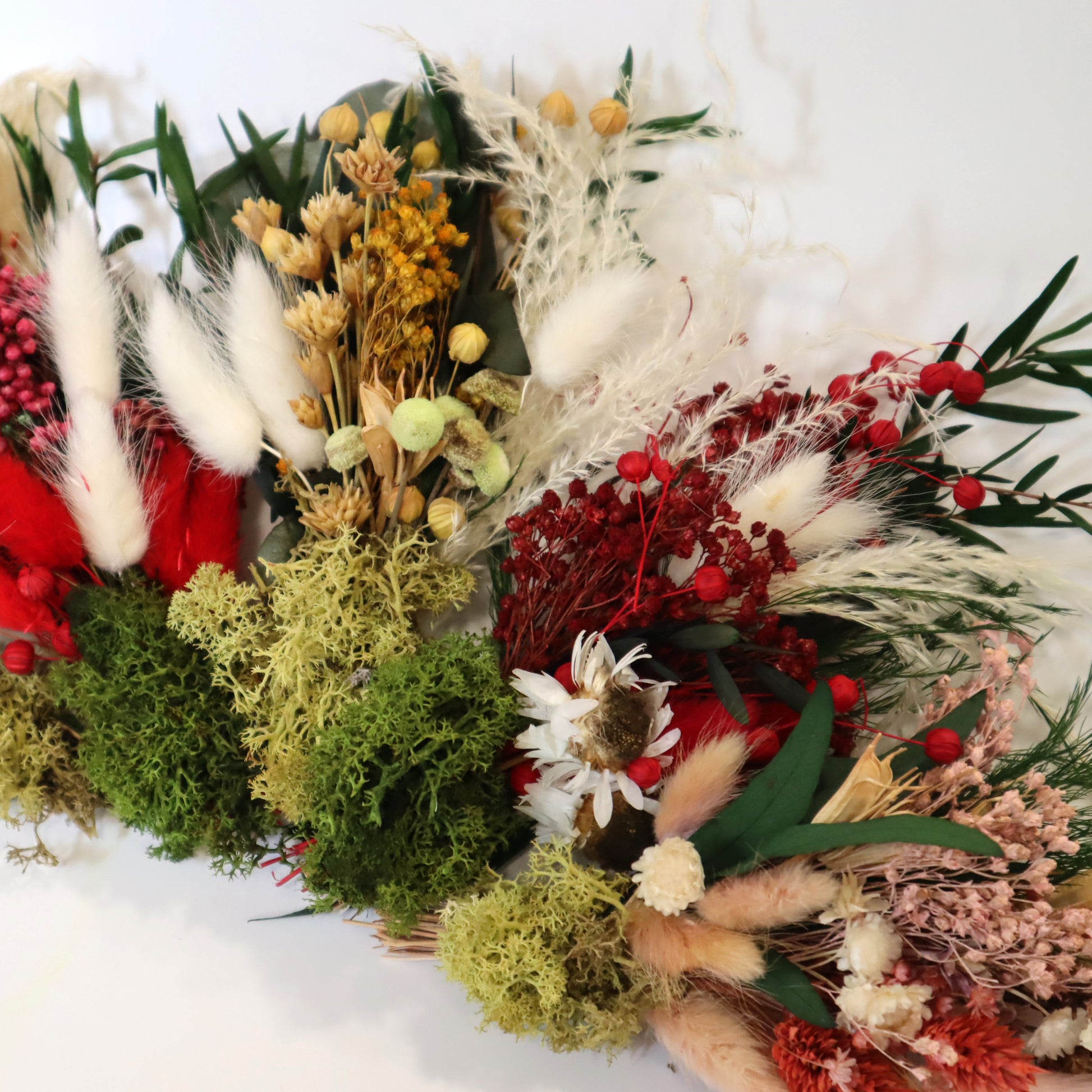 Dried flower bunches of varting different colours with preserved green moss wrapped around the bases