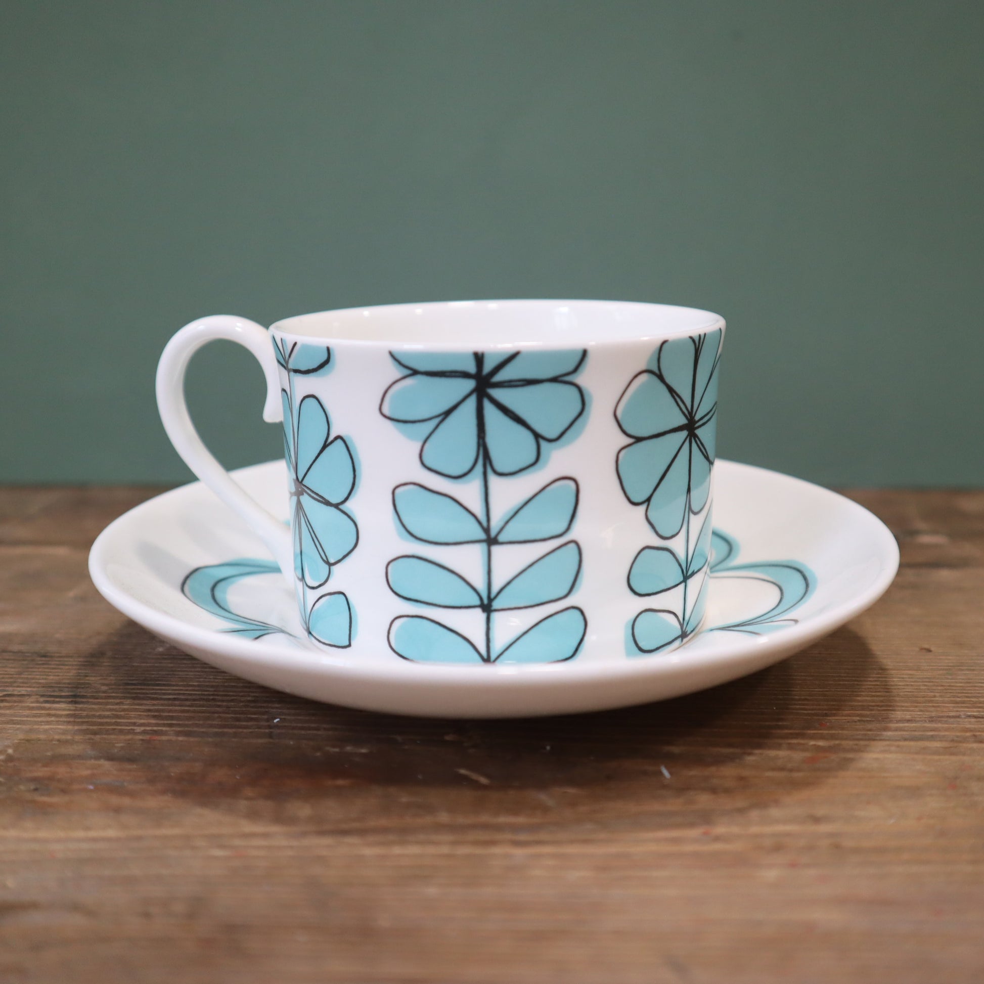Ceramic cup and saucer with blue floral pattern on a wooden surface