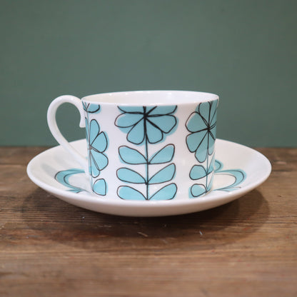 Ceramic cup and saucer with blue floral pattern on a wooden surface