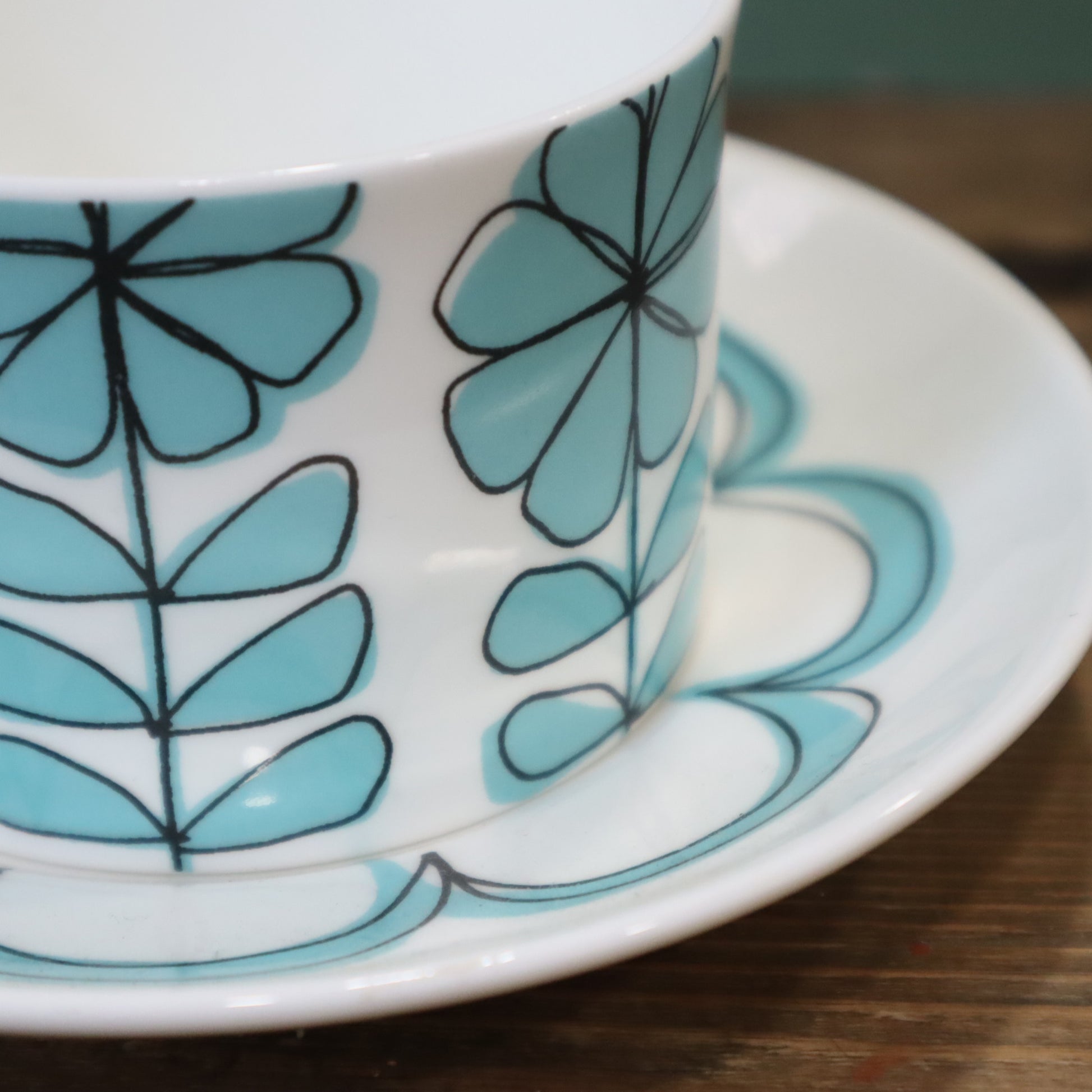 Teacup and saucer with blue floral pattern on a wooden surface