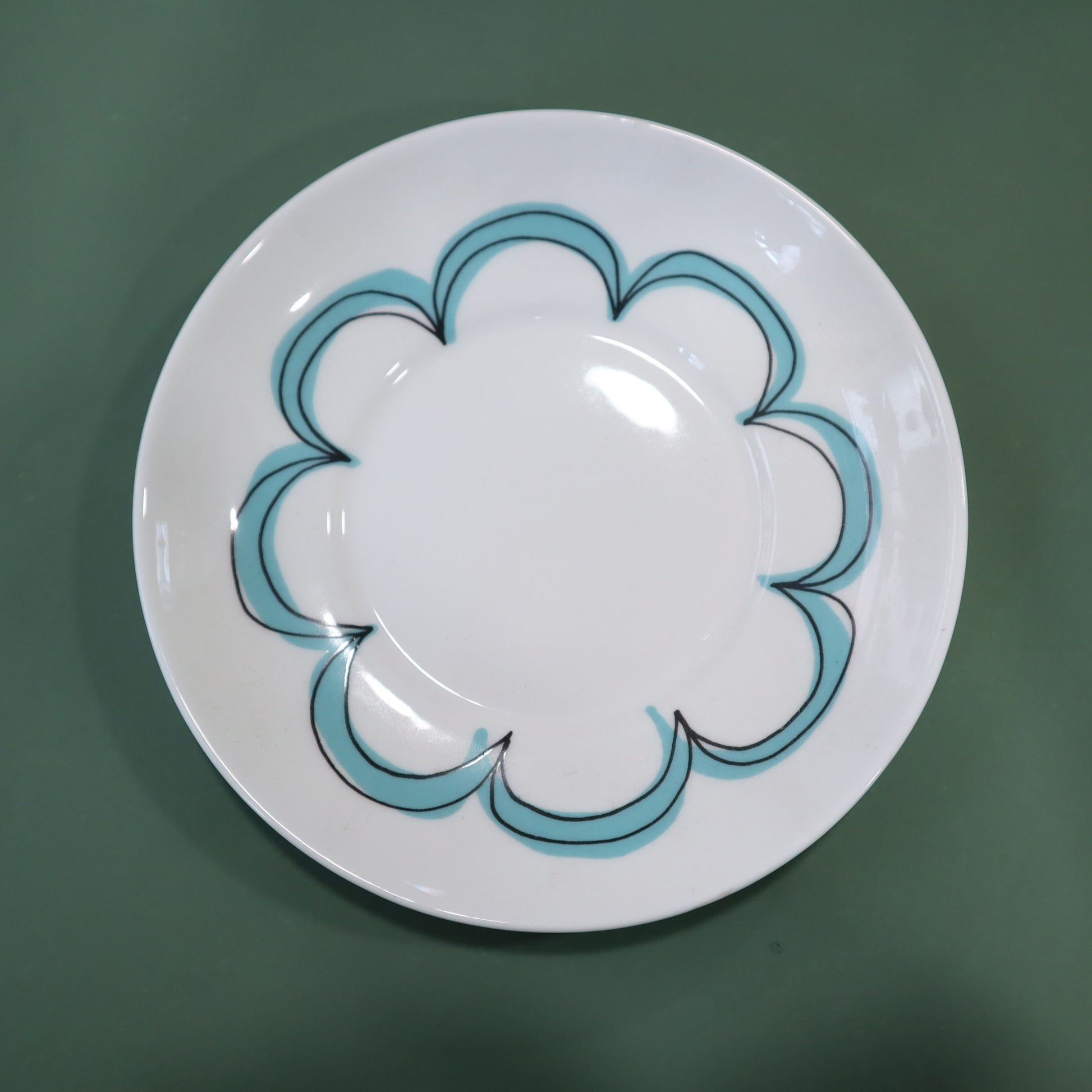 White plate with blue decorative rim on a green background