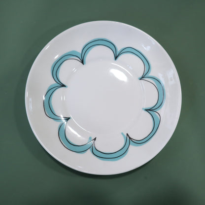 White plate with blue decorative rim on a green background