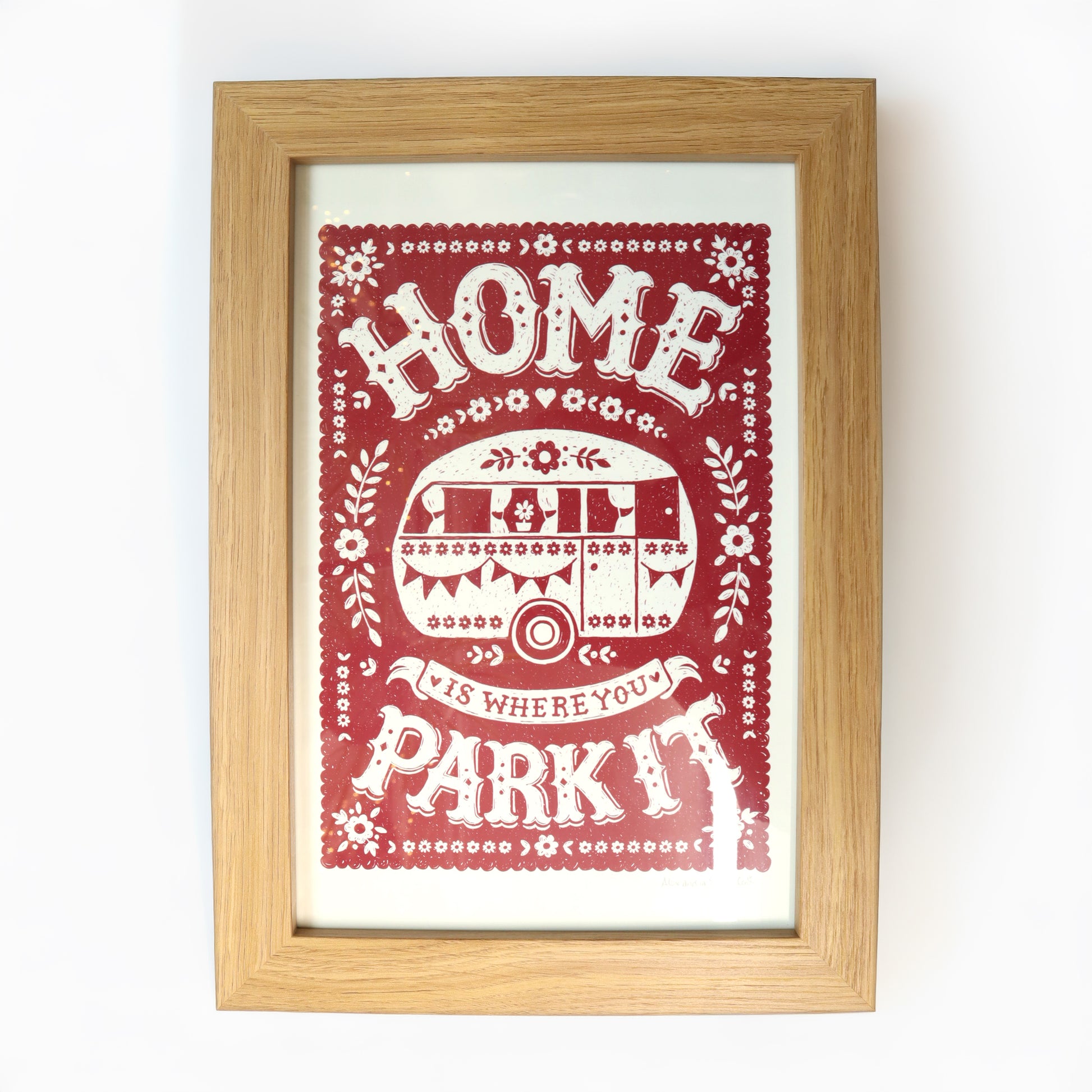 Framed print with 'Home is where your park it' text and graphic on a red background.