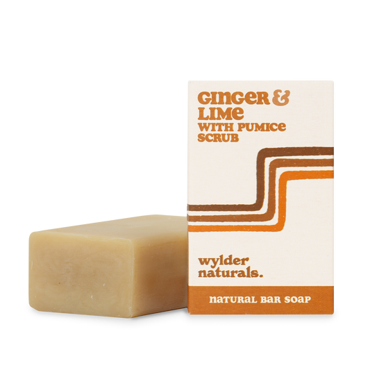 A natural bar soap. The packaging is beige with orange and brown accents, and text reads 'Ginger & Lime with Pumice Scrub, natural bar soap, wylder naturals'.