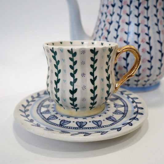 Patterned cup and saucer with gold handle