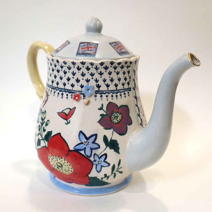 Highly decorated hand painted teapot against a white background