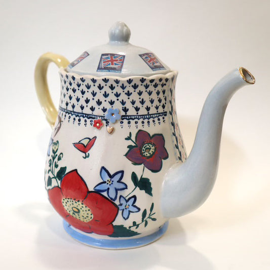 Highly decorated hand painted teapot against a white background