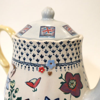 Decorative teapot with floral patterns and British flags on a white background