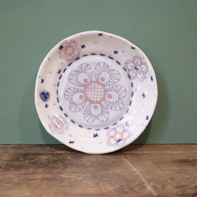 Decorative ceramic plate with floral patterns on a wooden surface and green background