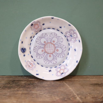 Decorative ceramic plate with floral patterns on a wooden surface and green background