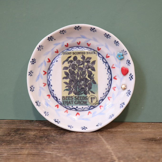 Decorative plate with vintage seed packet design on a wooden surface and green background