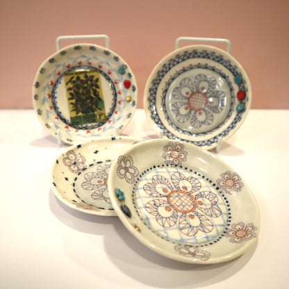 Set of four decorative ceramic plates with floral patterns on a white surface.