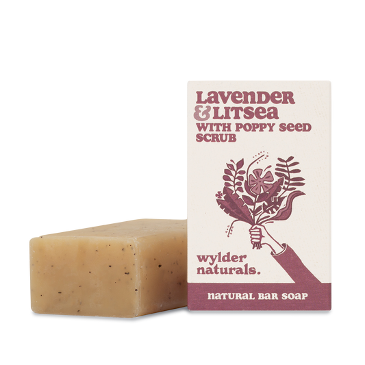 A natural bar soap with poppy seed scrub, next to its packaging which has 'Lavender & Litsea' written on it, indicating the scent of the product.