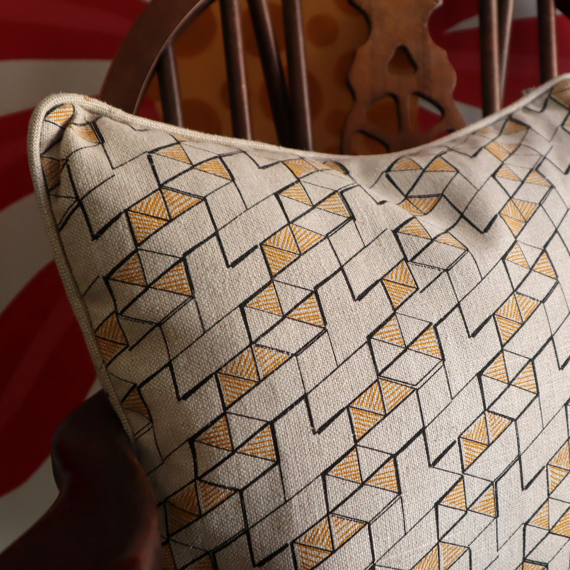 Decorative cushion with geometric pattern sat on a wooden chair against floral background