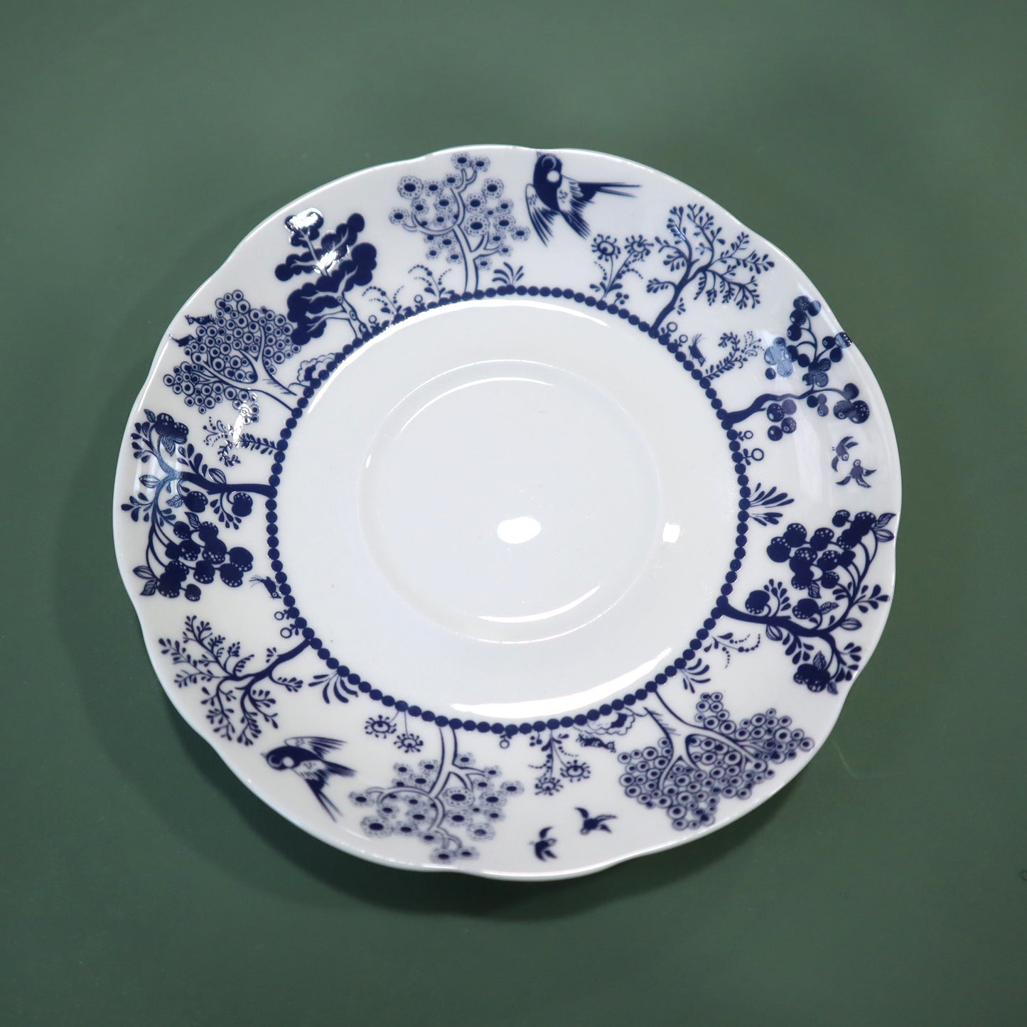 White plate with blue floral and bird pattern on a green background