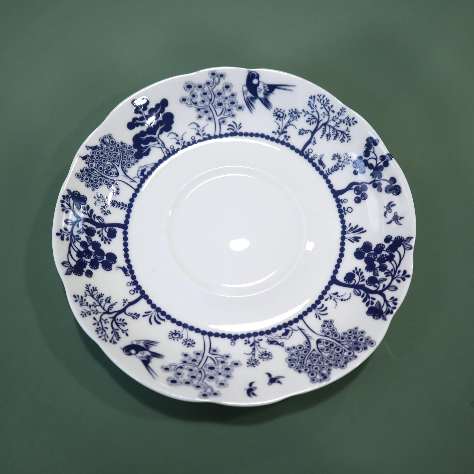 White plate with blue floral and bird pattern on a green background