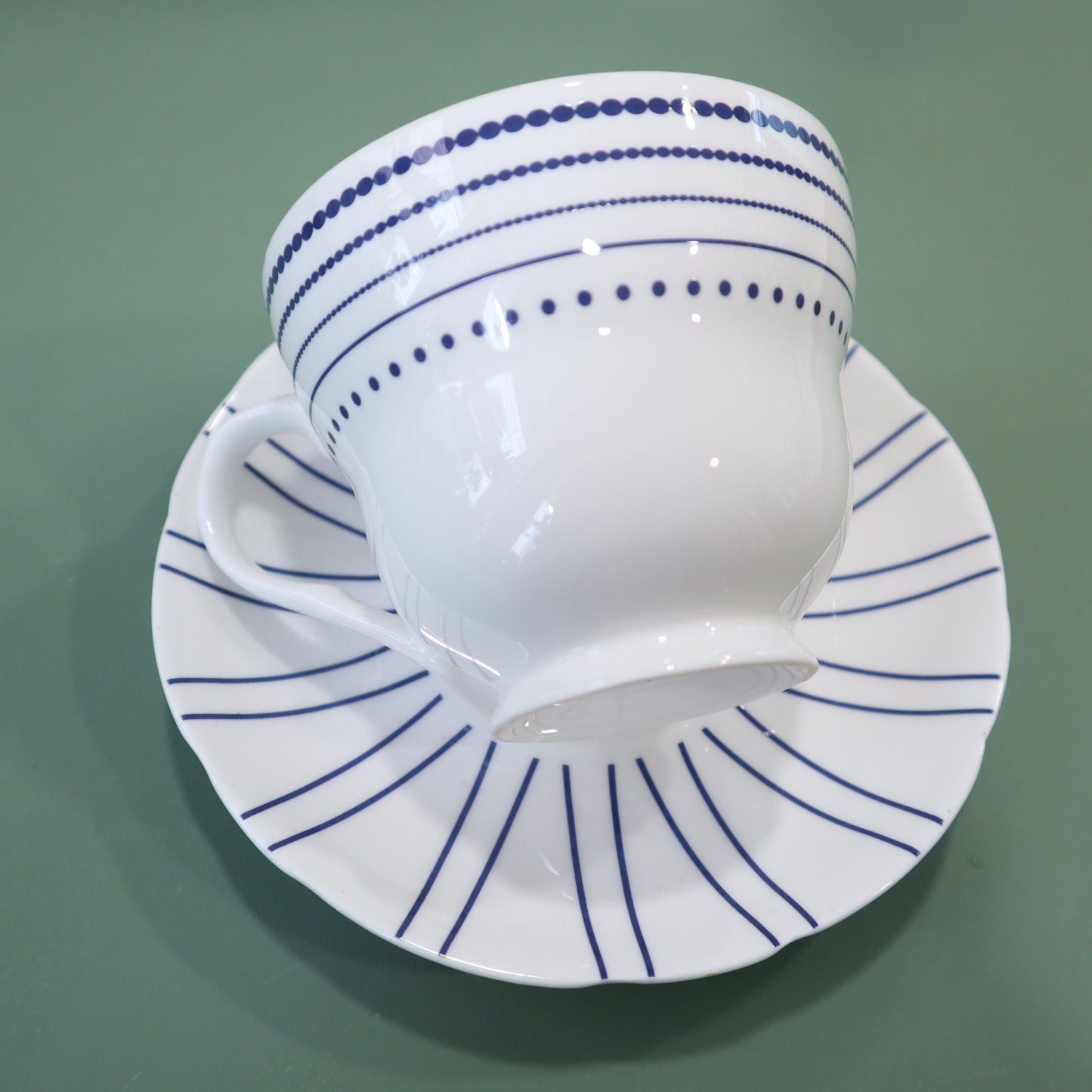 White cup and saucer with blue patterns on a green background