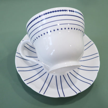 White cup and saucer with blue patterns on a green background