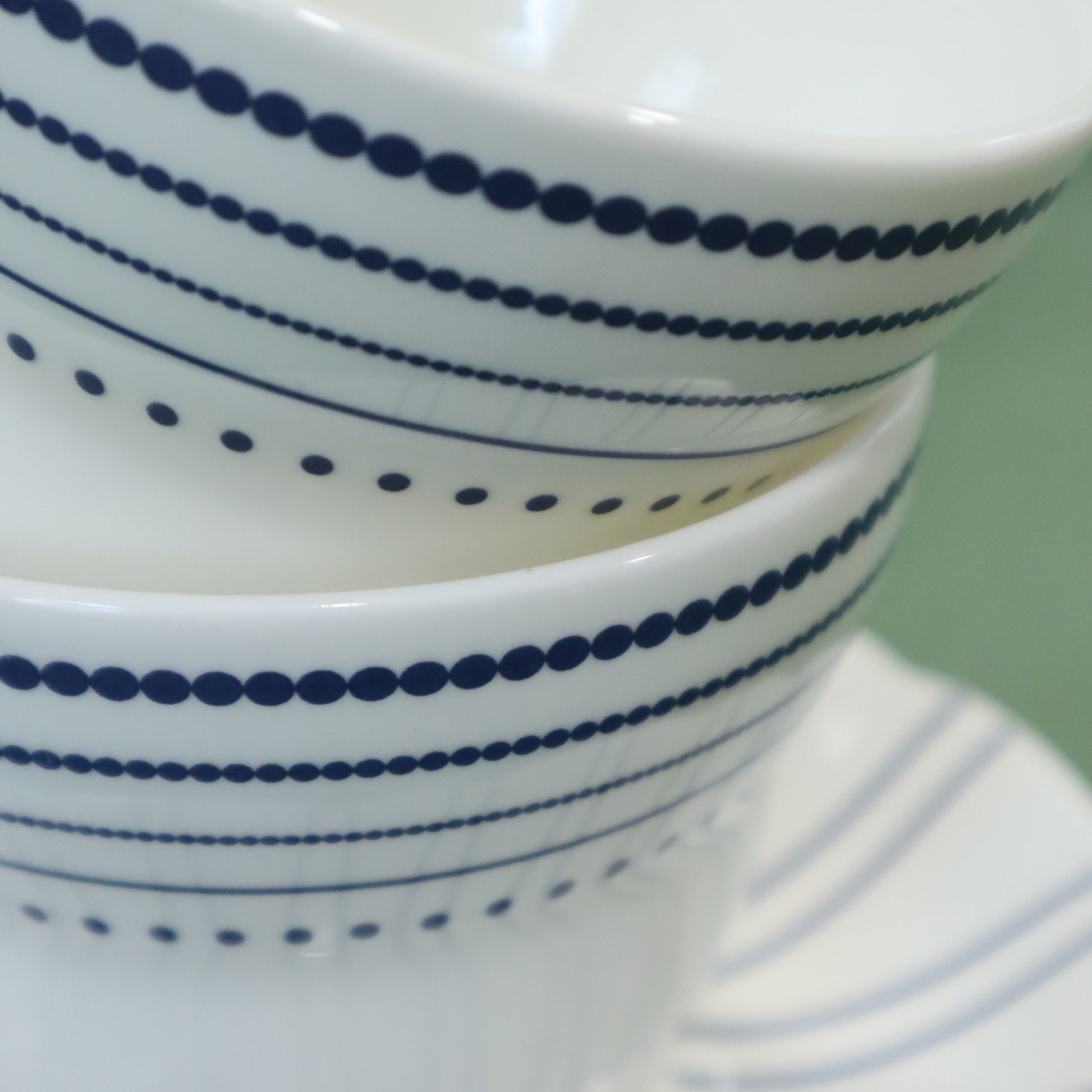 Stack of white bowls with blue stripes on a light green background