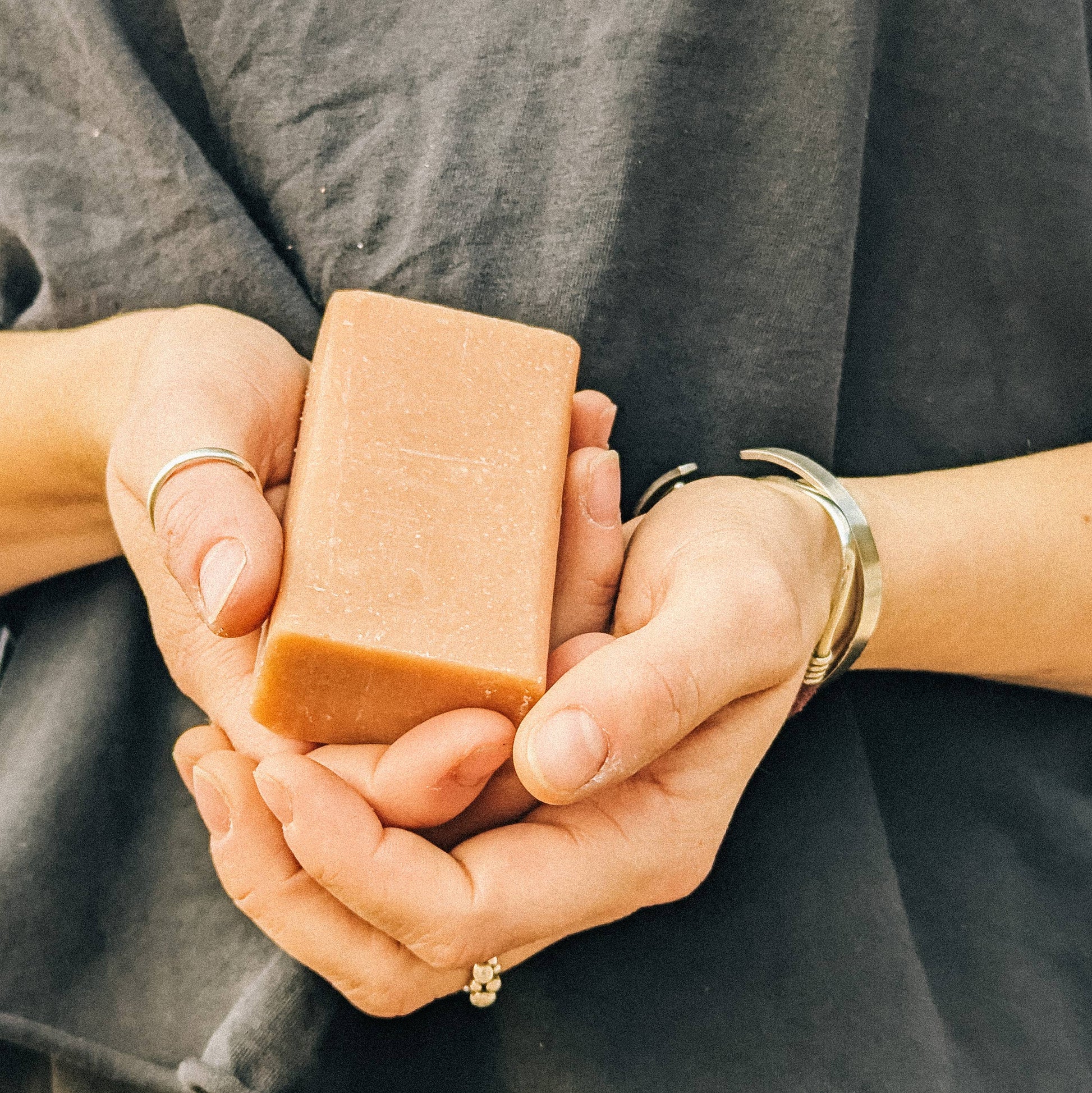 Someone holding a bar of soap against a dark grey t-shirt