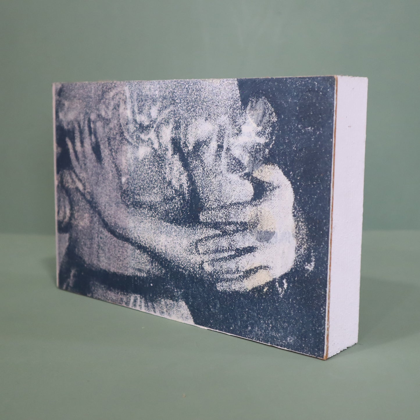 Wooden block with a textured print of two people hugging on a green background
