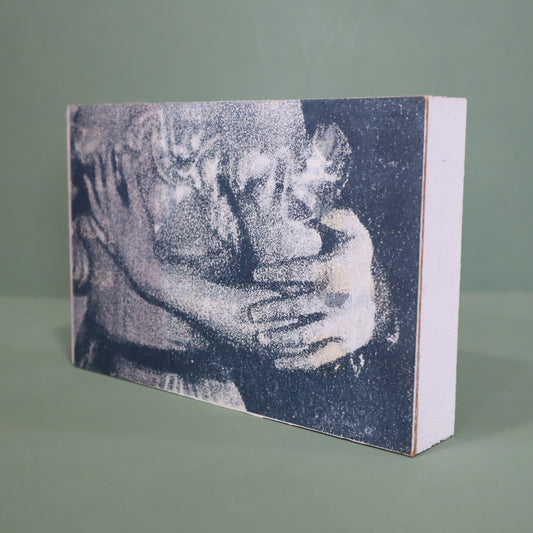 Wooden block with a textured print of two people hugging on a green background