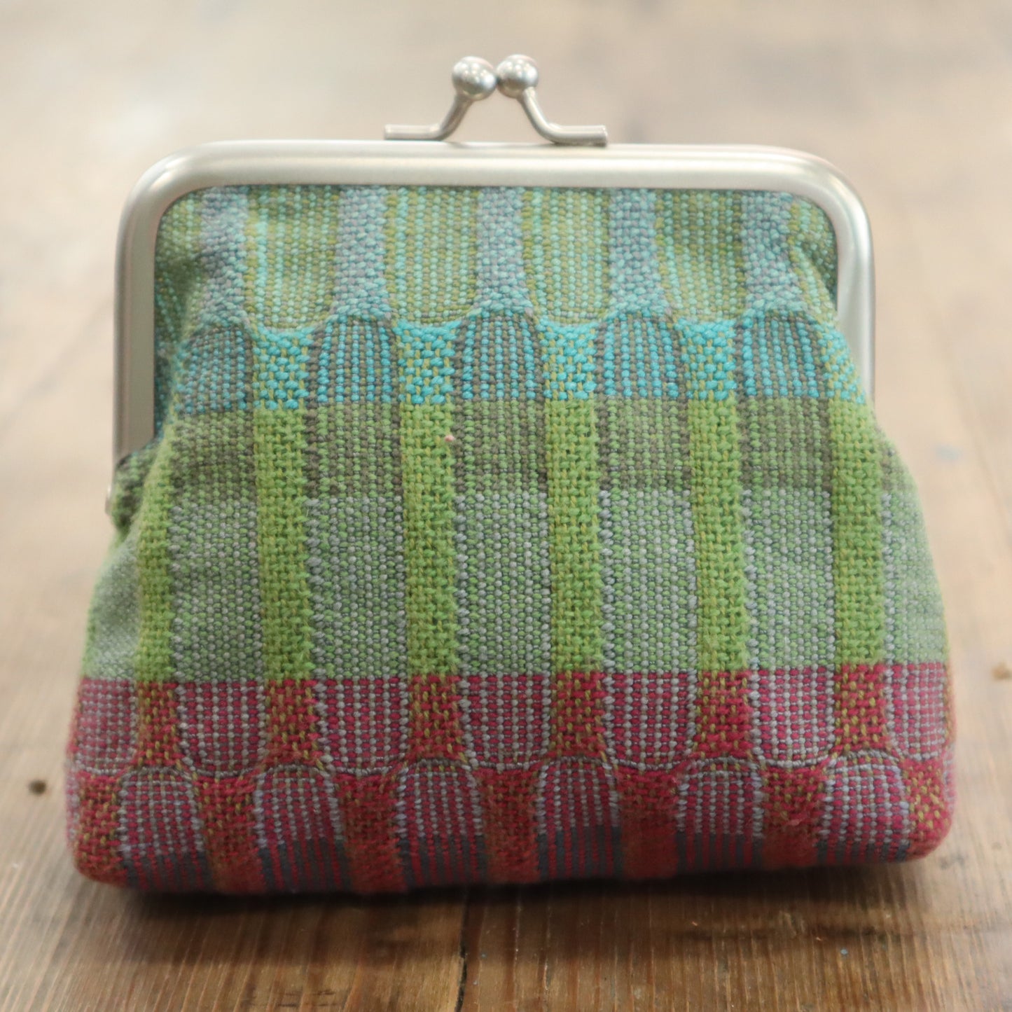 Multicolored woven purse on a wooden surface