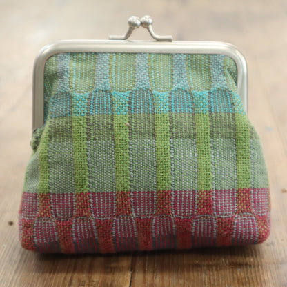 Multicolored woven purse on a wooden surface
