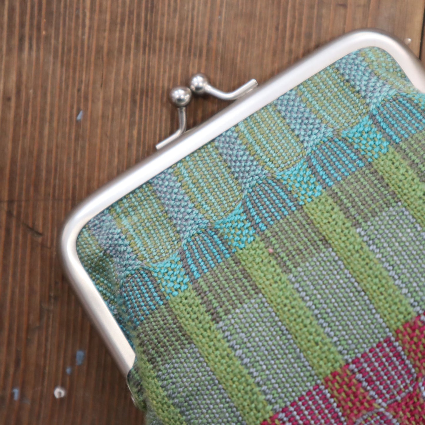 Textured fabric pouch with a metal clasp on a wooden surface