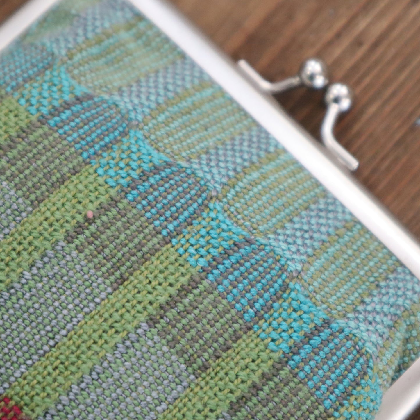 Close-up of a textured fabric with a metal clasp on a wooden surface