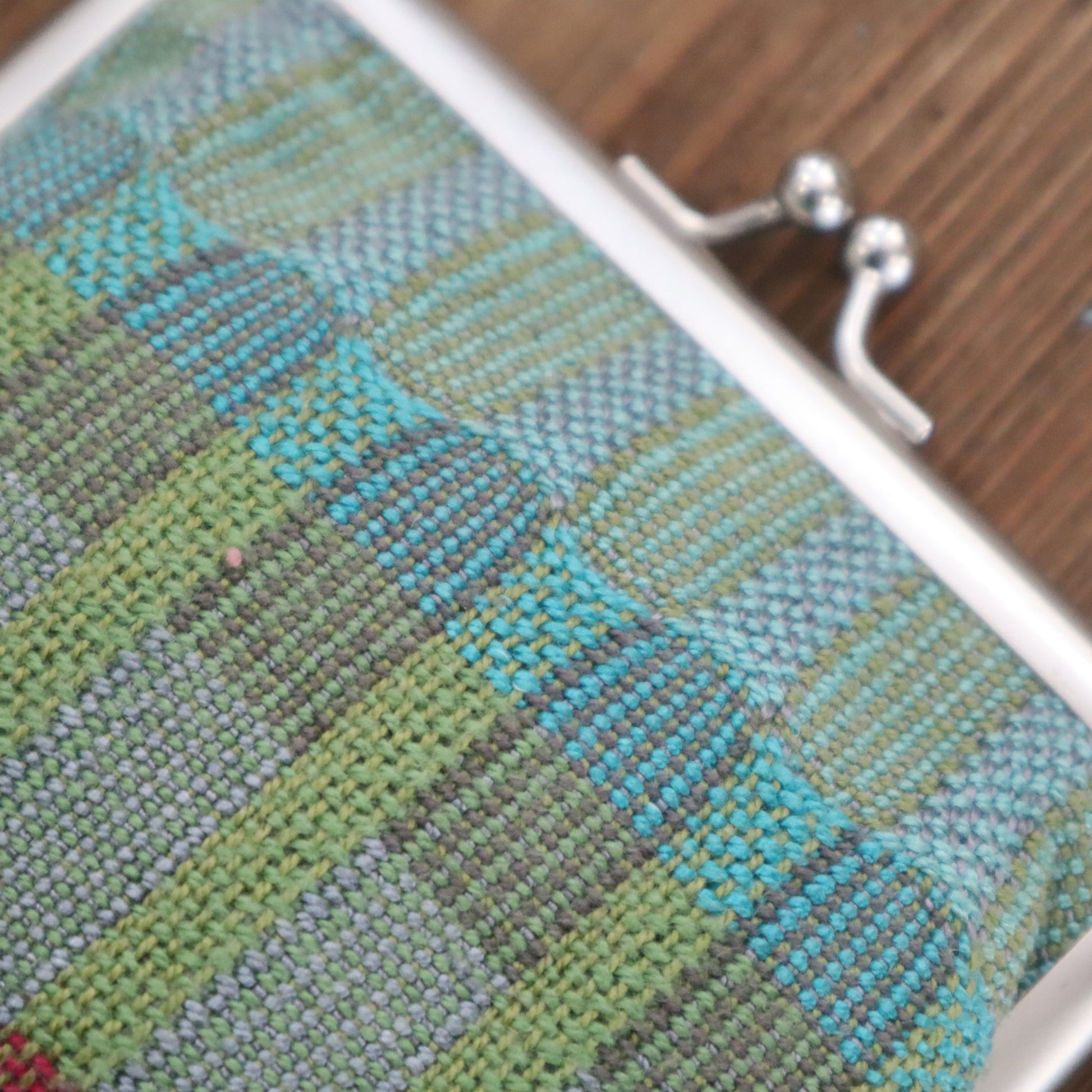 Close-up of a textured fabric with a metal clasp on a wooden surface