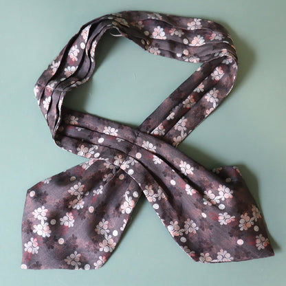 Floral patterned scarf tied into a bow on a light green background