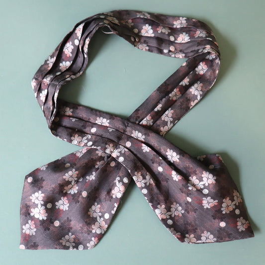 Floral patterned scarf tied into a bow on a light green background