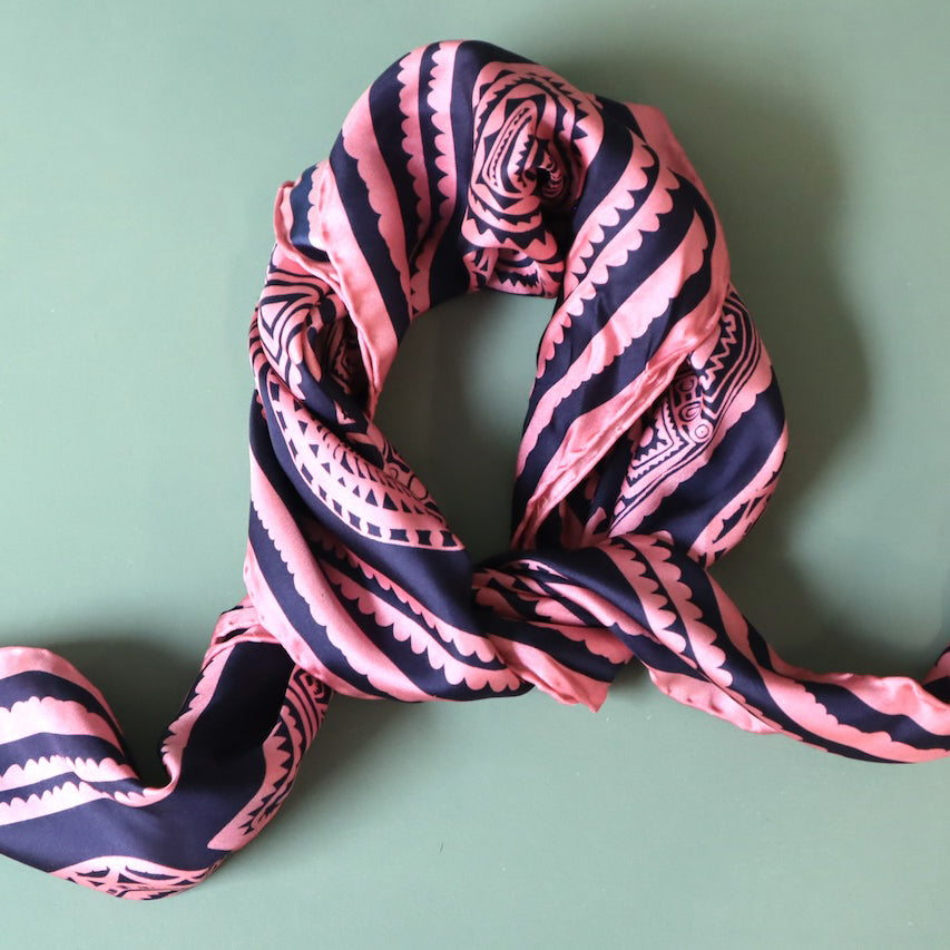 Pink and navy patterned scarf on a green background