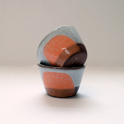 Two ceramic egg cups with a speckled design on a plain background