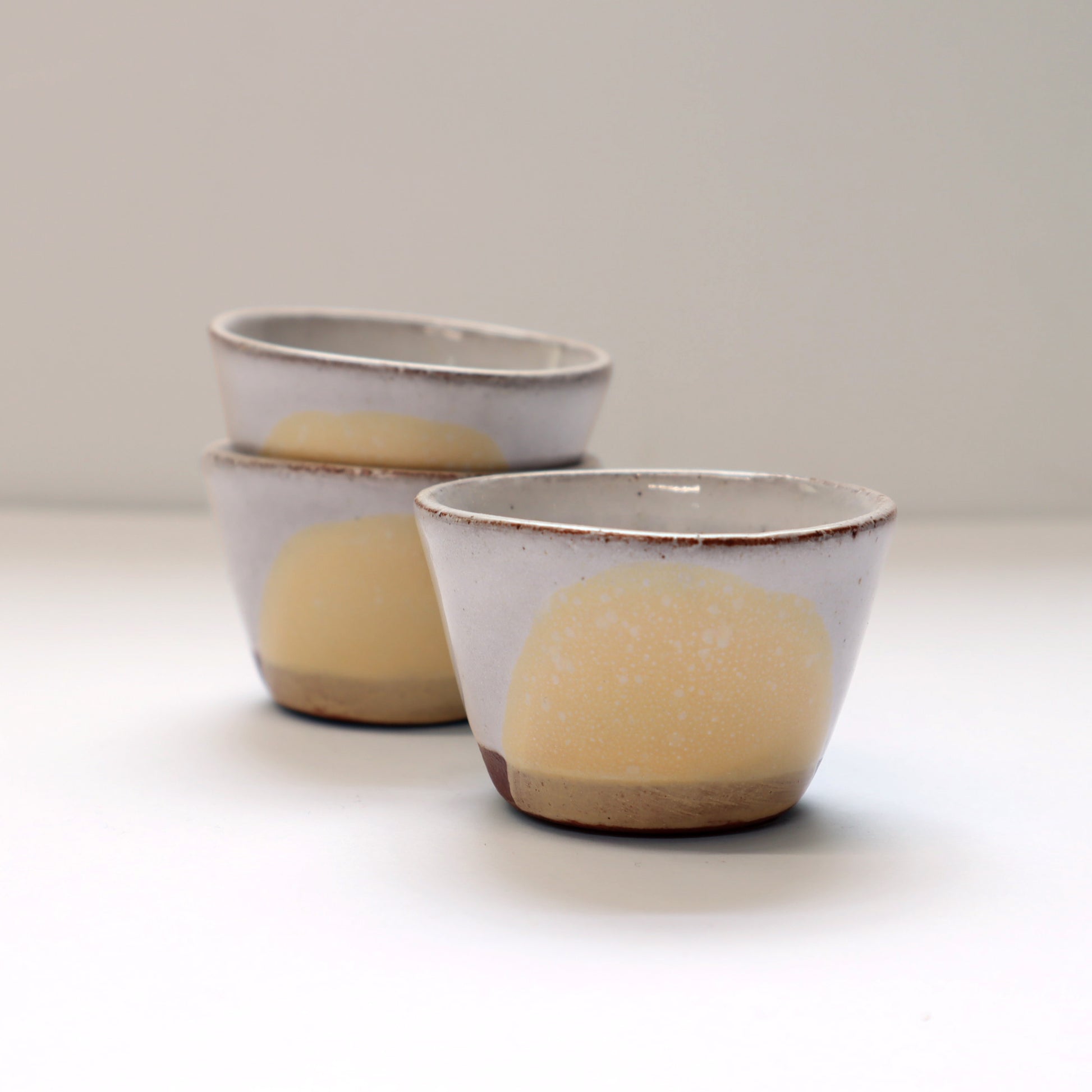 Three ceramic egg cups with a yellow circle design on a white background