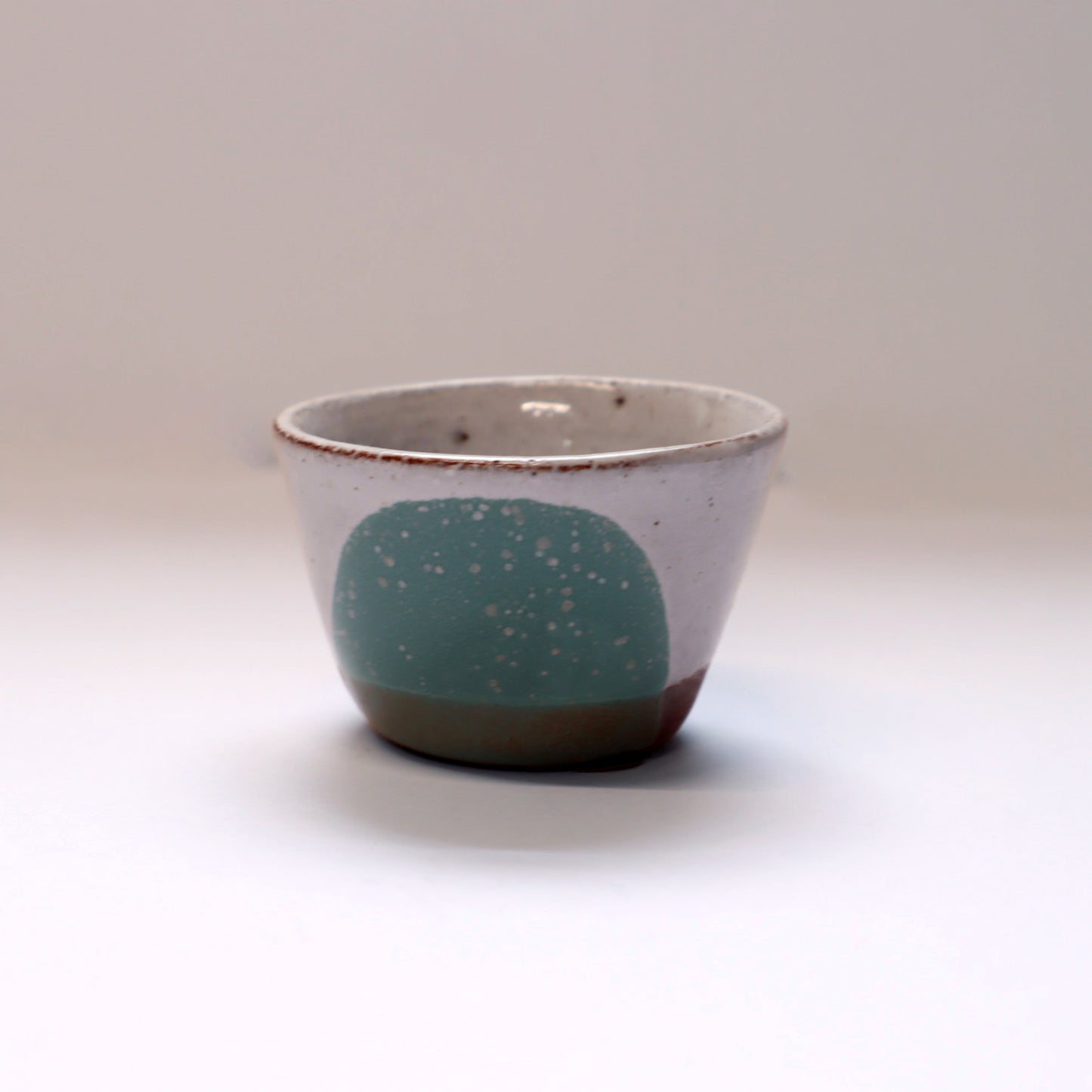 Ceramic egg cup with a green accent on a plain background