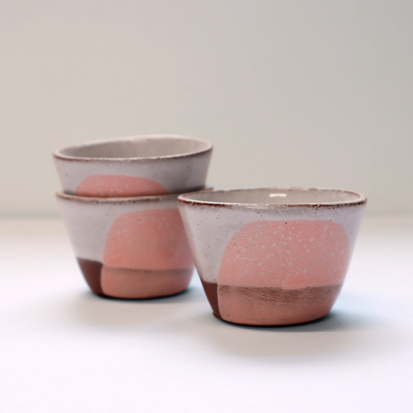 Three ceramic egg cups with pink and brown design on a white background