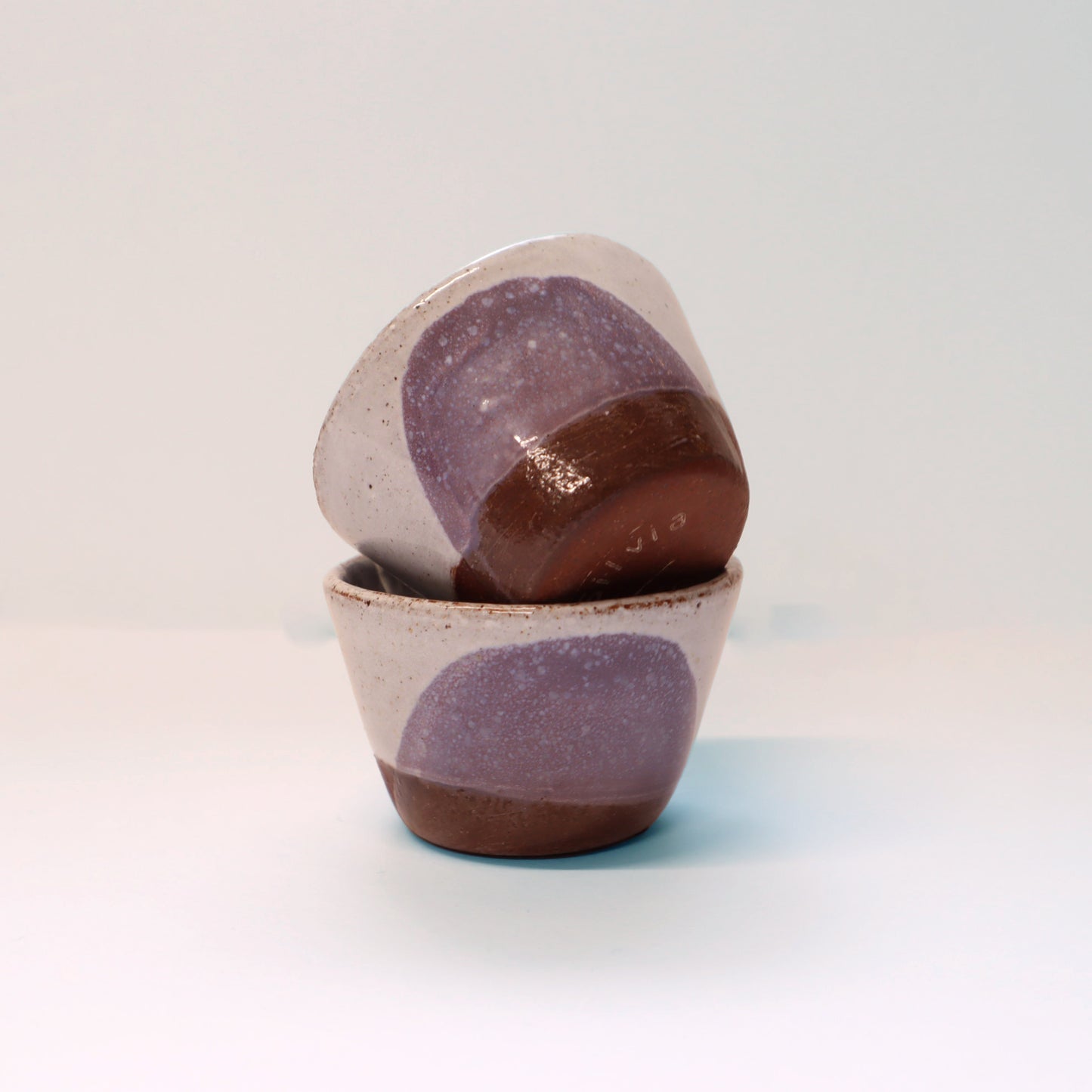 Two ceramic egg cups with purple and brown speckled design on a light grey background