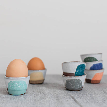 Ceramic egg holders with colorful designs on a wooden surface