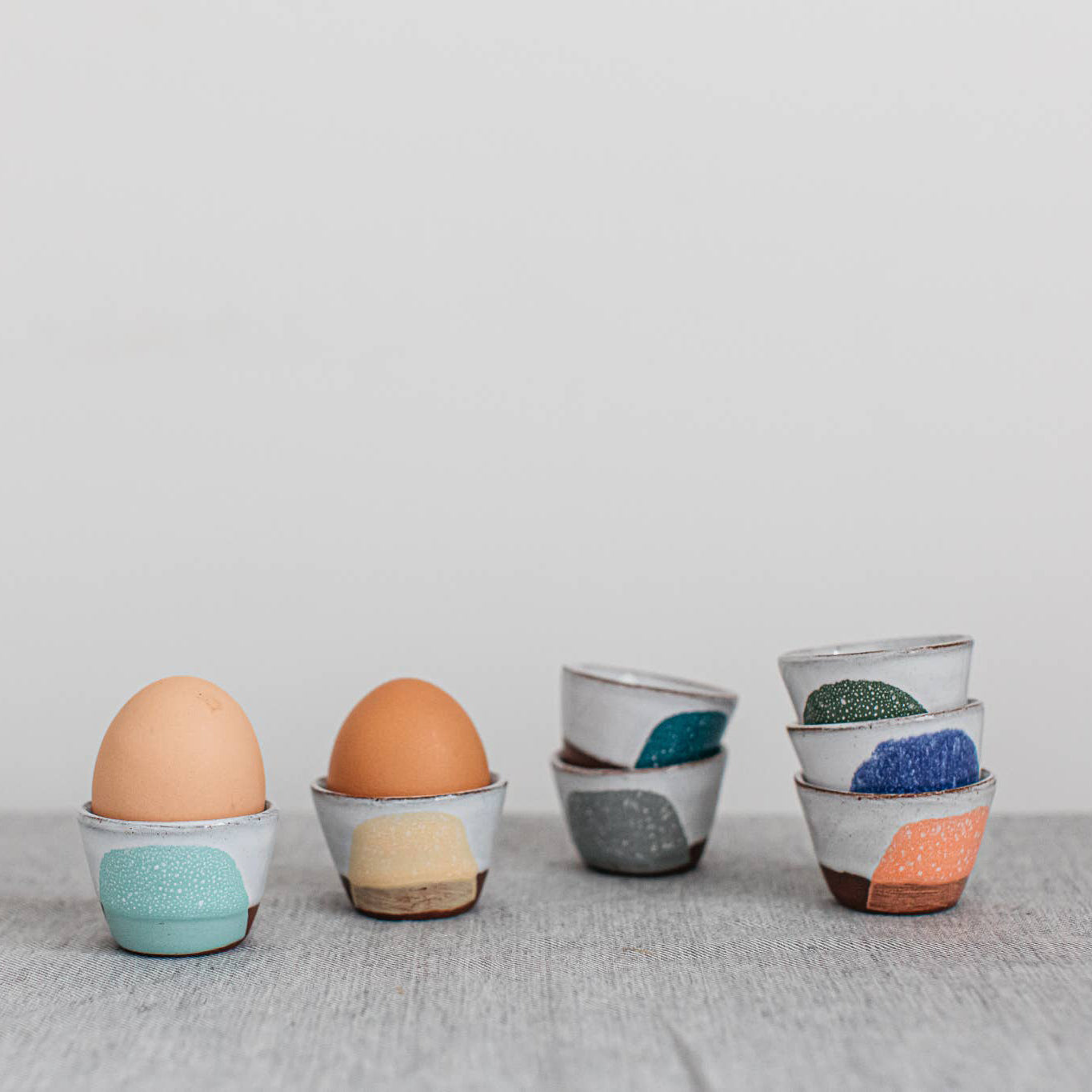 Four ceramic egg cups with colorful patterns on a gray surface