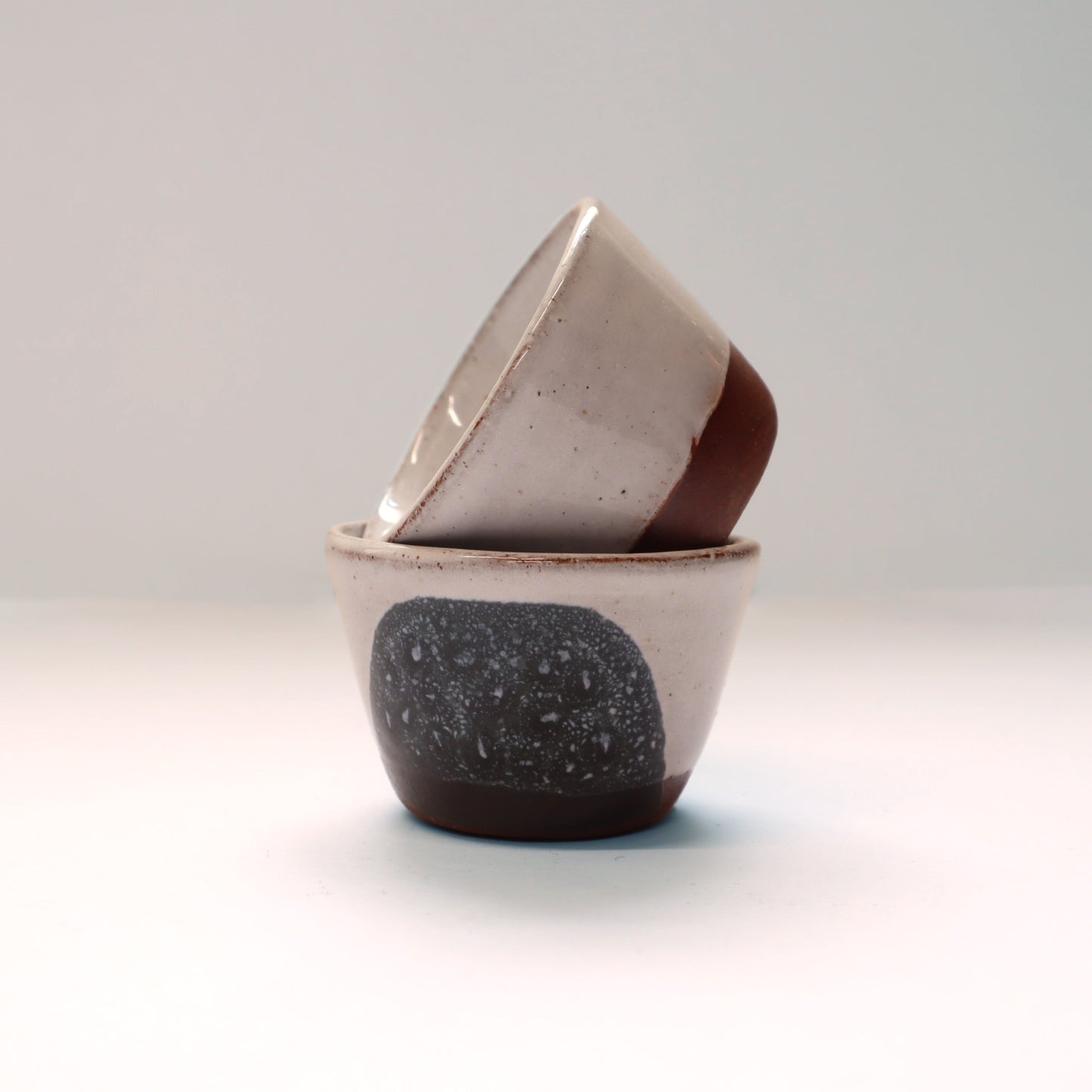Two ceramic egg cups stacked on a light gray background