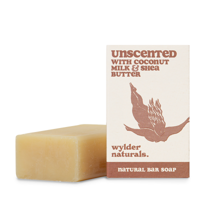 A bar of natural soap with a label that reads 'Unscented with Coconut Milk & Shea Butter', indicating it is a bar of natural soap with simple, eco-friendly packaging.