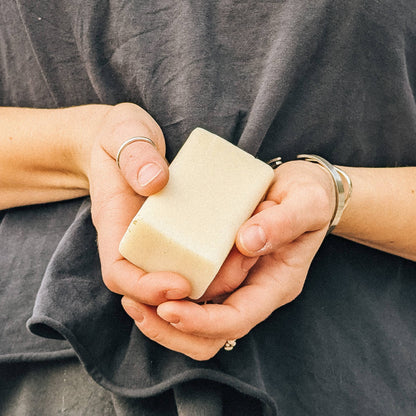 Someone holding a bar of soap with both hands in front of a dark grey t-shirt