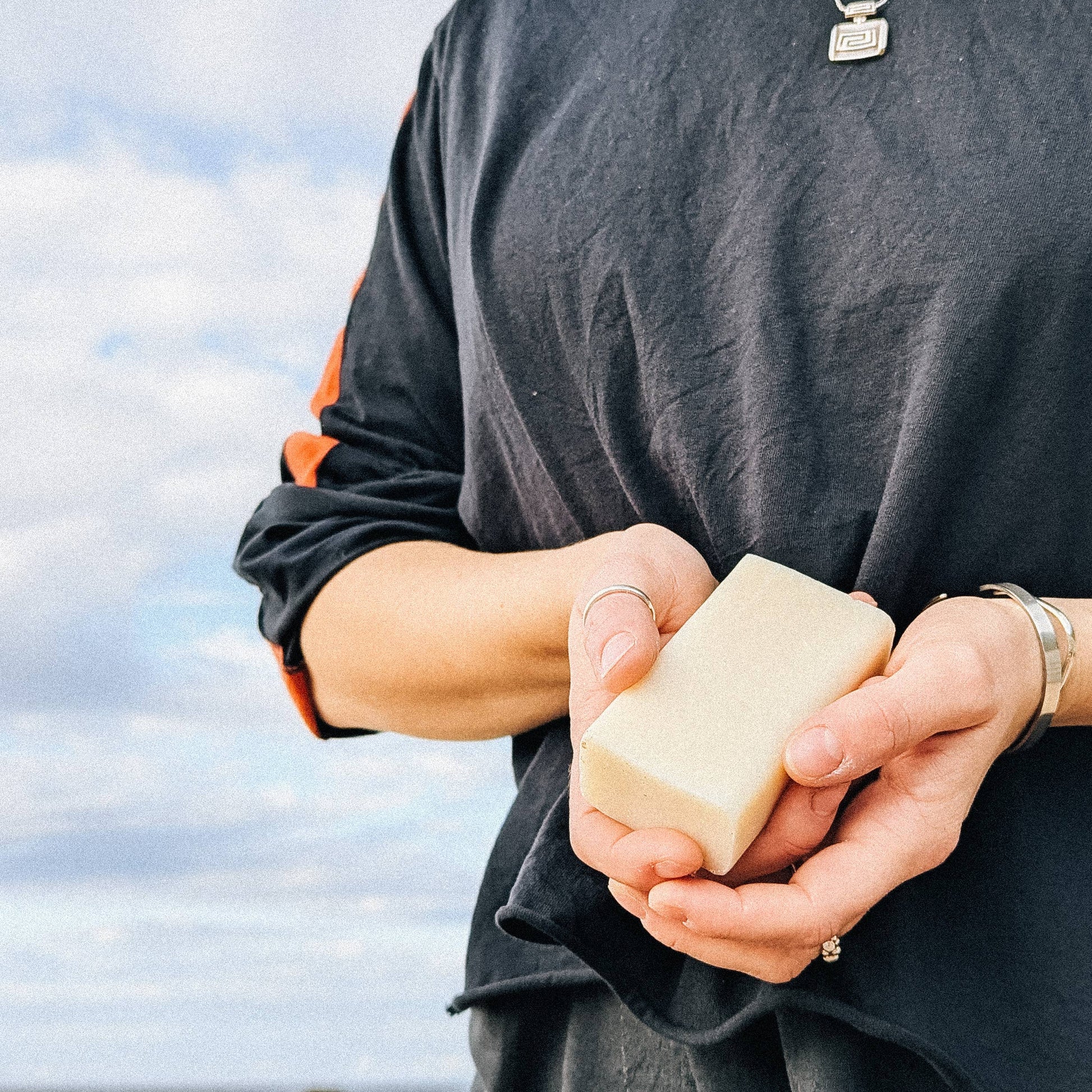 Two hands holding a bar of soap against themselves wearing a dark grey t-shirt